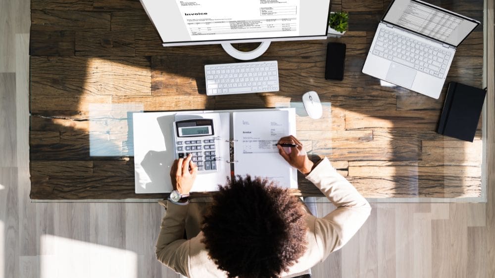 Guide to Nova Scotia Government Contractor Payment Terms - arial view of businessperson reviewing invoices.