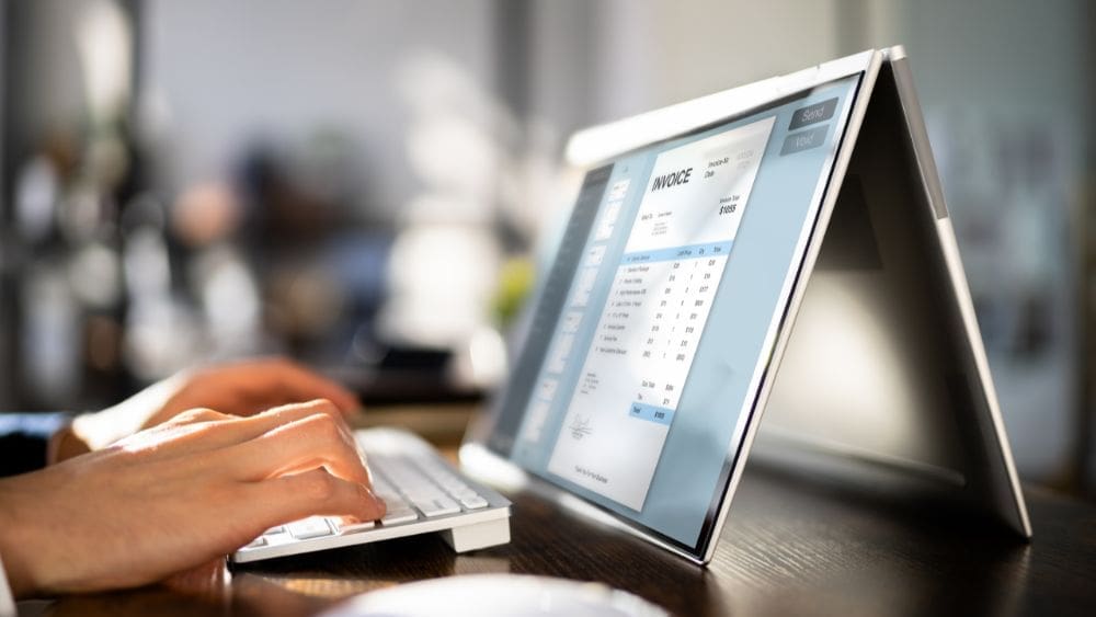 Newfoundland and Labrador Government Contractor Payment Terms Guide - hands typing on tablet keyboard with invoice on tablet screen.